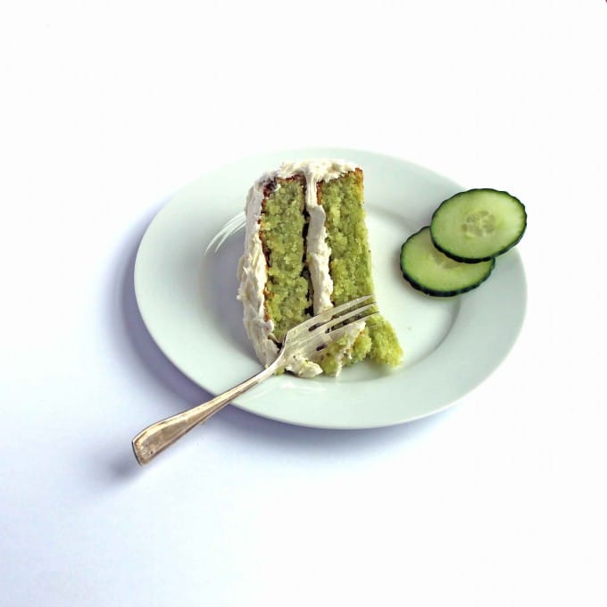 A piece of cake on a plate, with cucumber slices.