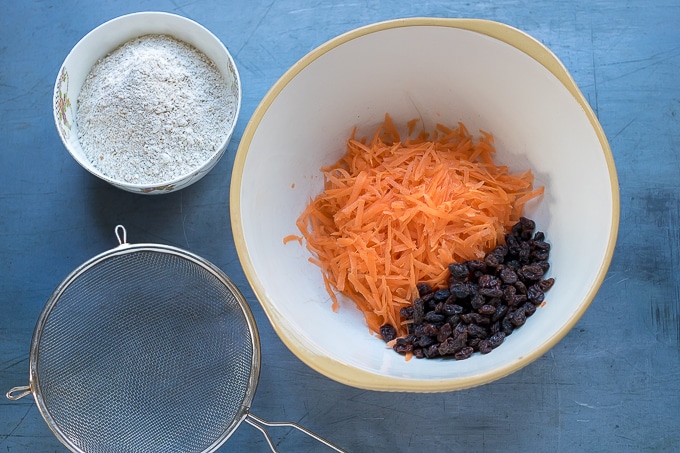 How to make easy carrot cake: Step 1 - Add grated carrot and raisins to a bowl