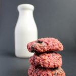 A stack of cookies in front of a milk bottle.