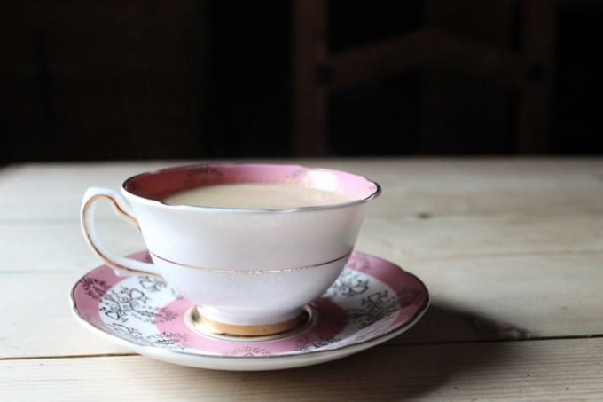 A table with a vintage teacup of cocktail.