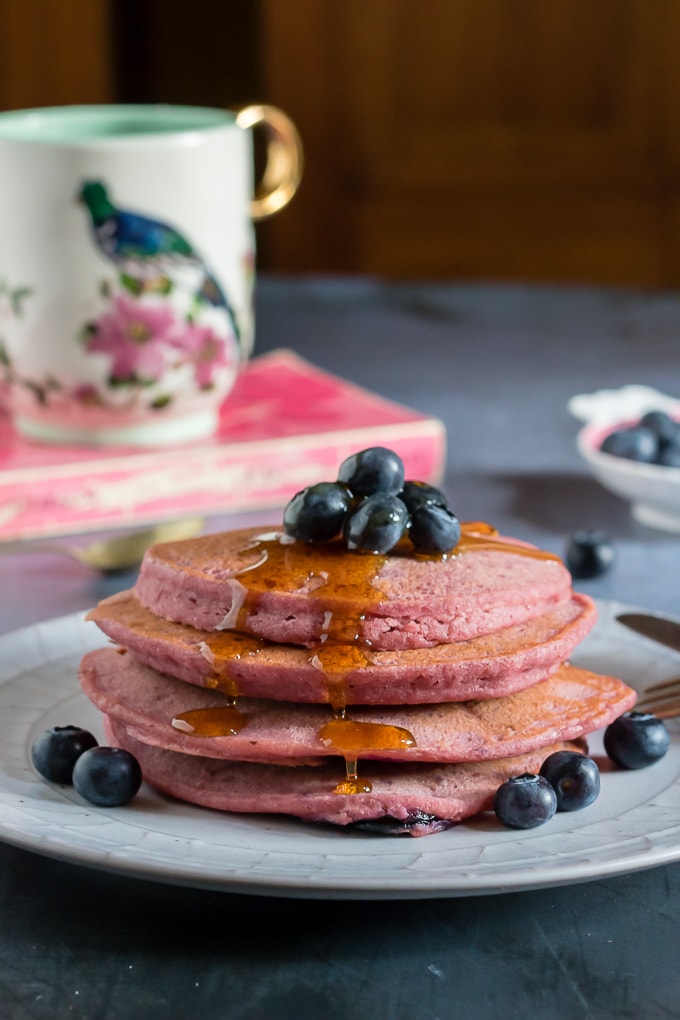 Stack of pancakes with blueberries and maple syrup.