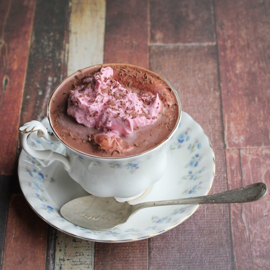 Red Velvet Beet Hot Chocolate with Beet and Vanilla Whipped Cream in a vintage teacup on a wooden table.