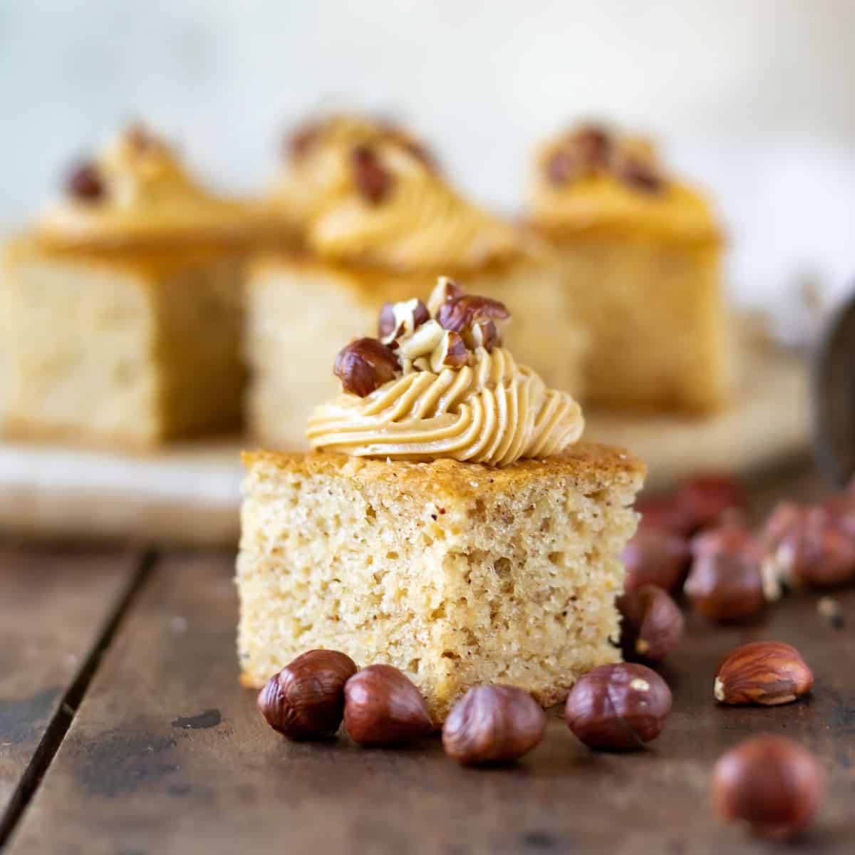 Slice of cake topped with frosting and hazelnuts.
