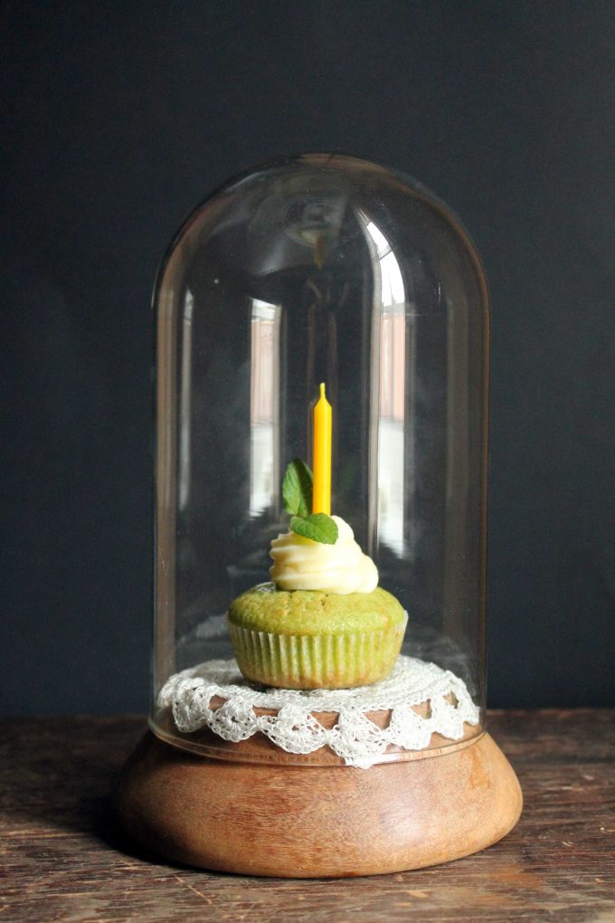 Mint cucumber cupcakes with rose frosting, in a bell jar with a candle.