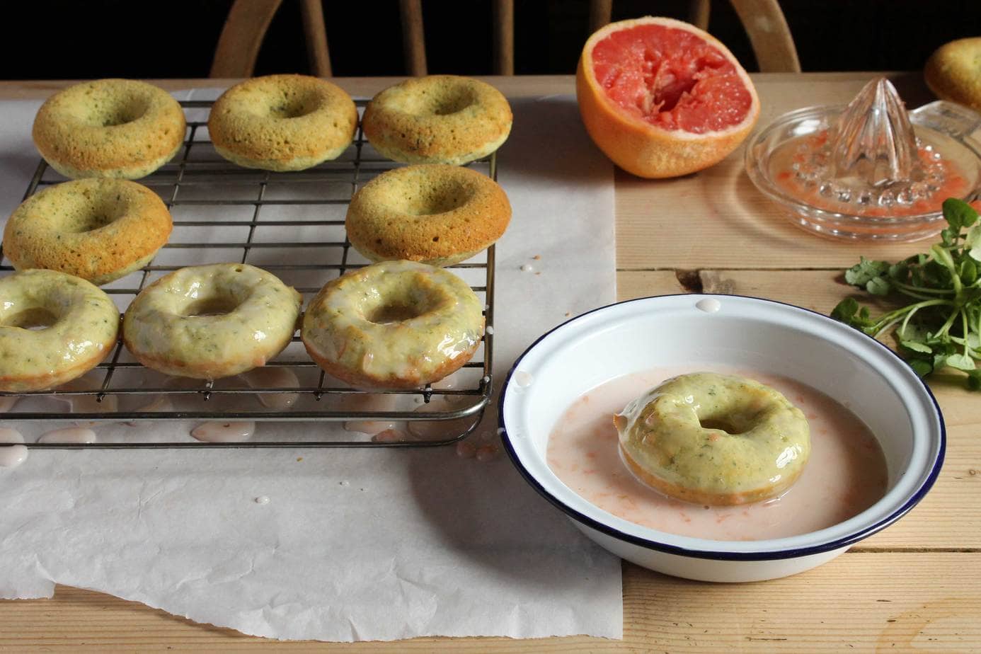 Donuts being dipped into citrus glaze.