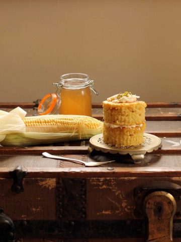 A mini layer cake next to a cob of corn.