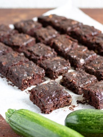 Close up of cut zucchini brownies with a zucchini in the front