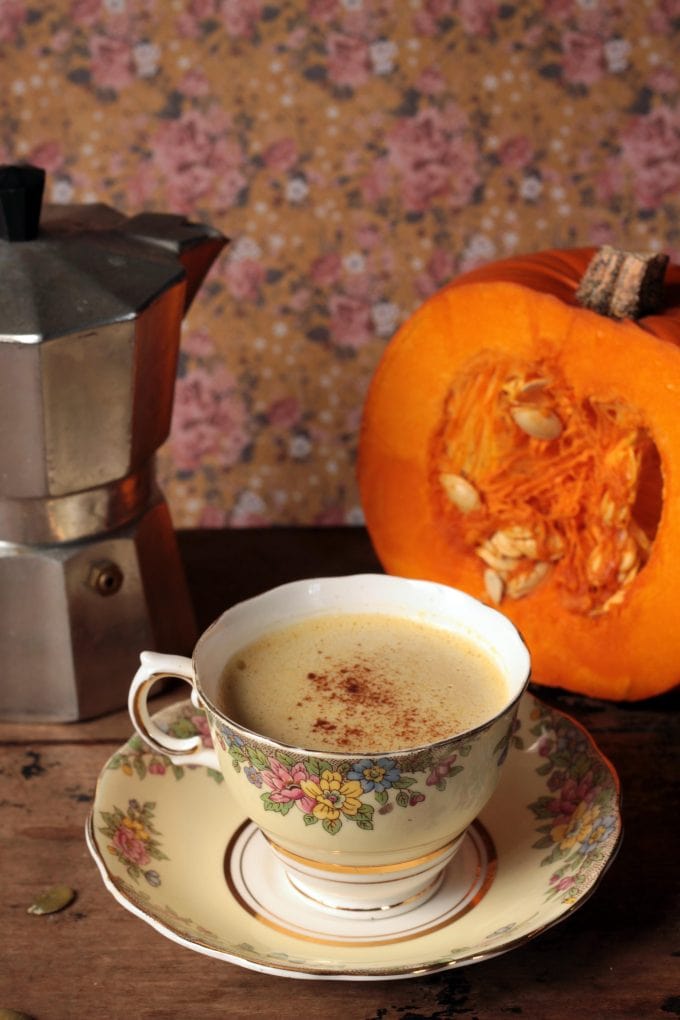 A table with a teacup, pumpkin and coffee pot.