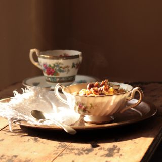 A table with a bowl of oatmeal and cup of tea.