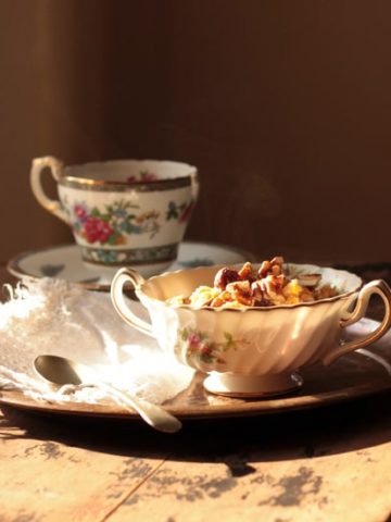 A table with a bowl of oatmeal and cup of tea.