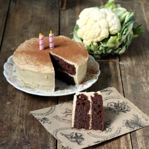 Cake on a table with a cauliflower in the background.