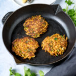 Moroccan Carrot Fritters in a skillet next to plates and cutlery