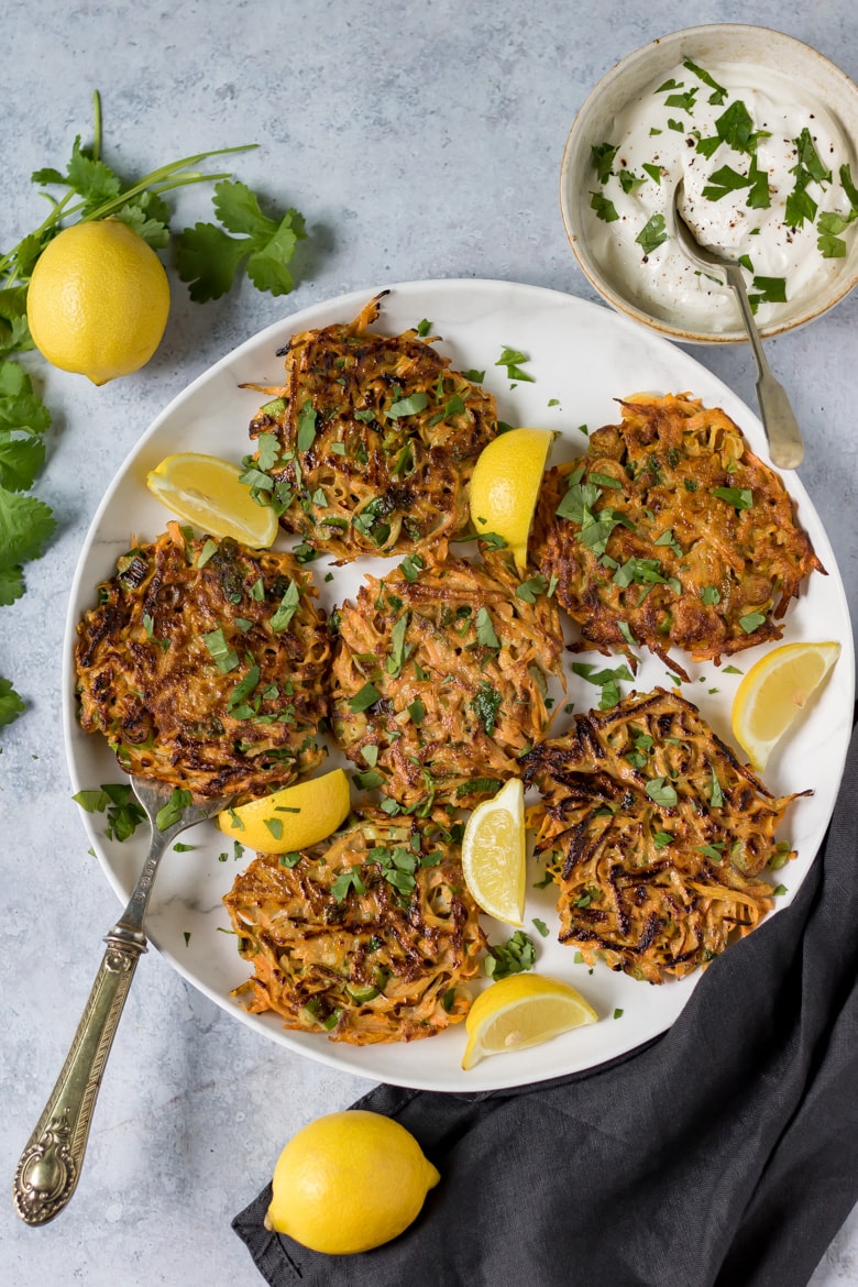 A plate of Moroccan spiced chickpea and carrot fritters, with wedges of lemon.