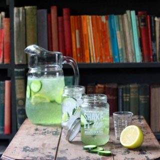A table with drinks and a jug, in front of bookshelves.