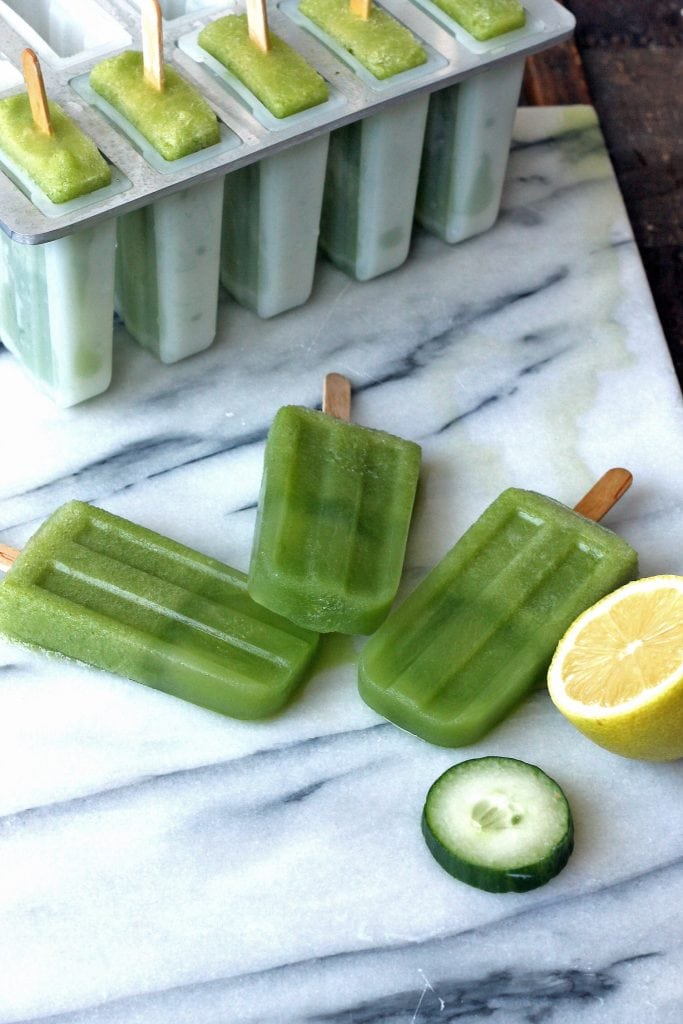 A marble board with three cucumber popsicles on it.