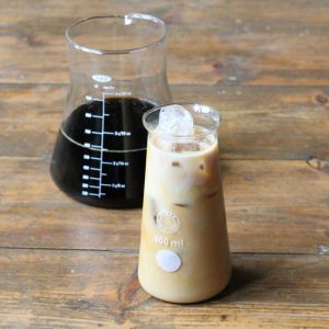 A glass of iced coffee in front of a carafe of coffee.