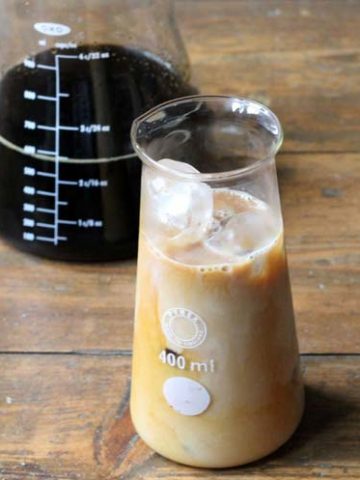 An iced latte in front of brewed coffee.