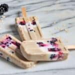 Three blackberry oat breakfast popsicles on a marble board.