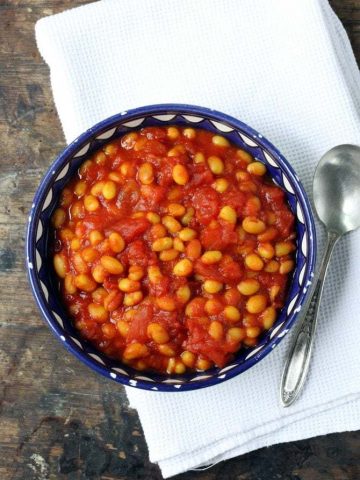 Bowl of baked beans on a table.