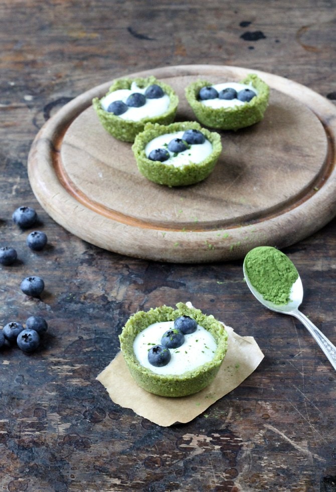 Tarts on a wooden board with one in front.