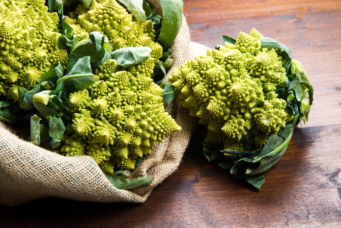 Romanesco vegetable falling out of a burlap sack onto a wooden board.