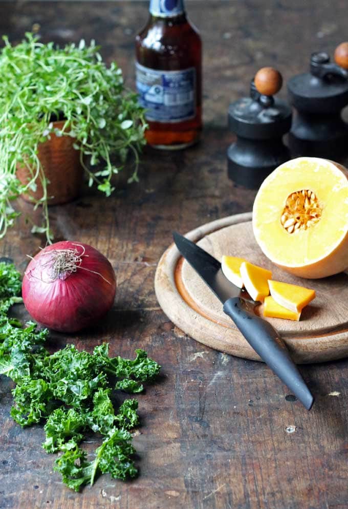 A table with a cut butternut squash and an onion.