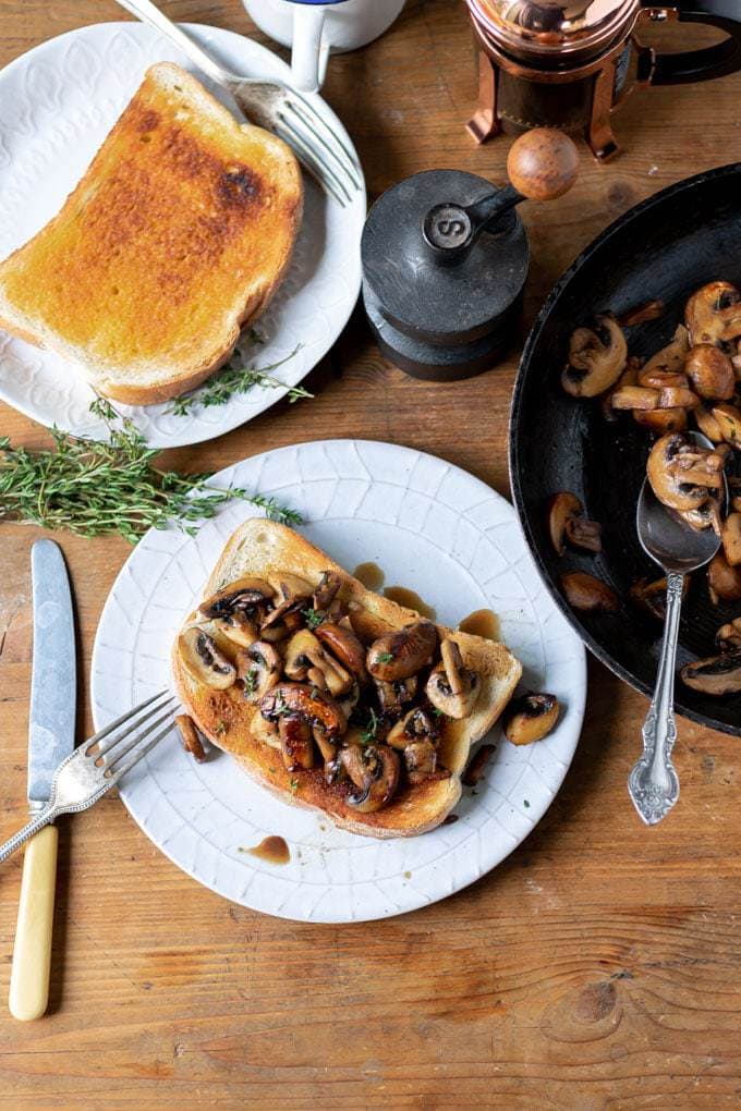 A plate of food on a wooden table, with mushrooms and toast.