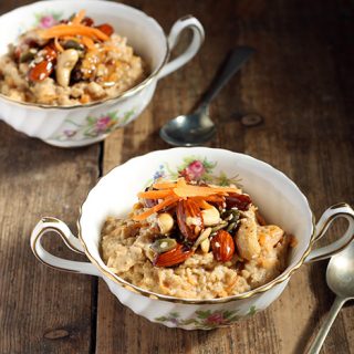 Two bowls of oatmeal topped with nuts.
