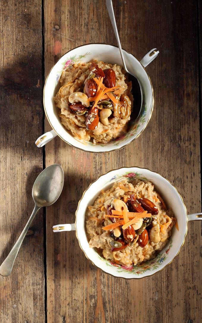 Two bowls of oatmeal topped with caramelised nuts and grated carrot.