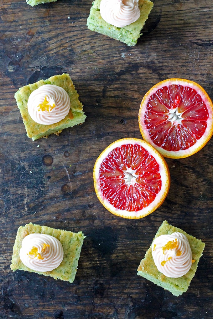 Squares of cake next to blood oranges cut open.