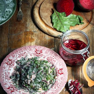 A plate of beet callaloo next to a jar of pickled beet stems.