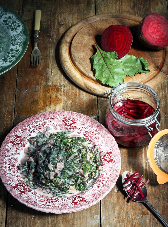 A plate of beet callaloo next to a jar of pickled beet stems.