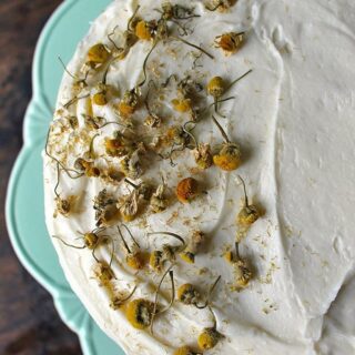 Chamomile Cake with Salted Honey Buttercream in a green vintage cake stand, decorated with chamomile tea