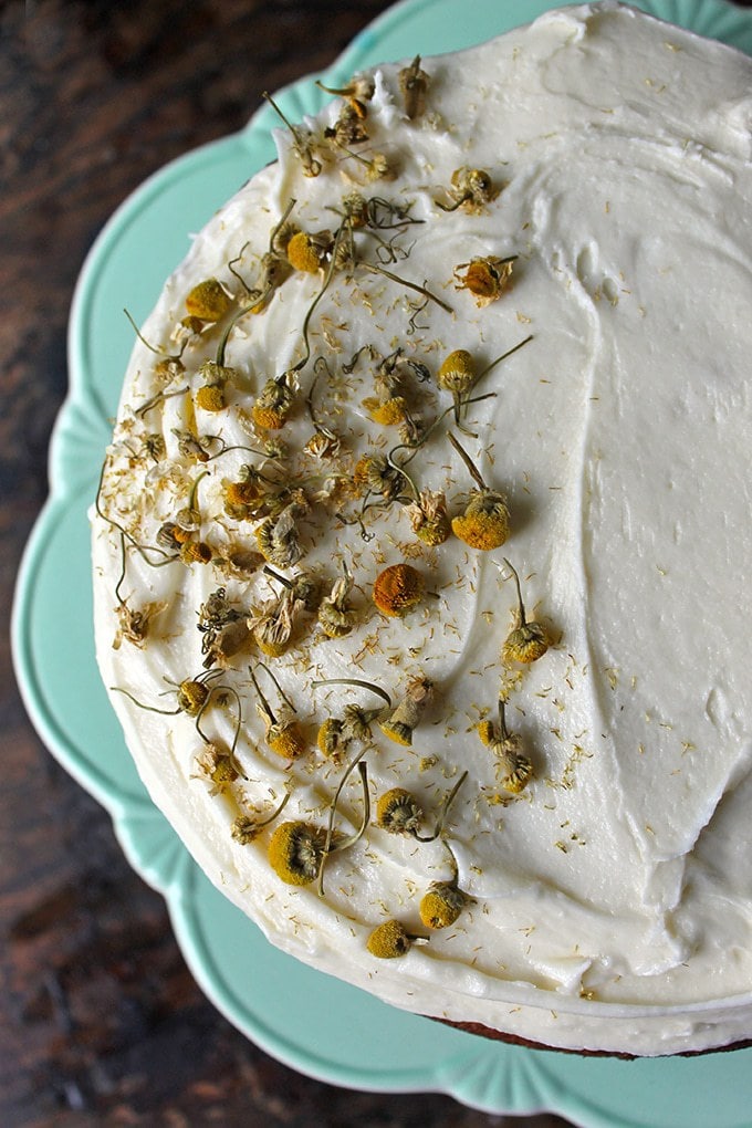 Close up of the top of a Chamomile Cake, on a vintage cake stand and decorated with chamomile buds.