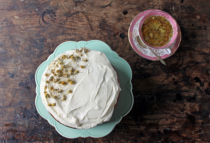 Cake on vintage cake stand next to a vintage cup of tea.