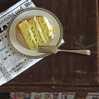 A slice of triple-layer cake on a plate on a wooden table.