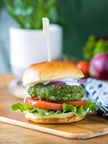 A pea spinach burger in a bun with lettuce, tomato, red onion and mayo. The vegan burger patty is bright green. Get the recipe now.