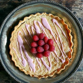 Pie topped with raspberries on a table.