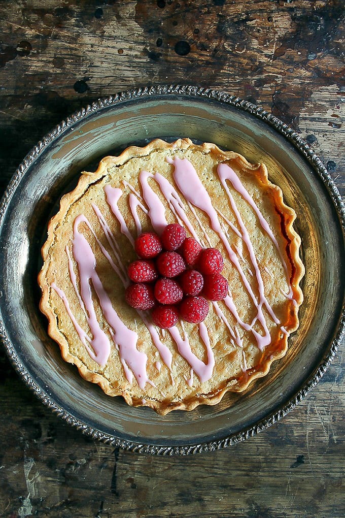 Pie topped with raspberries on a table.