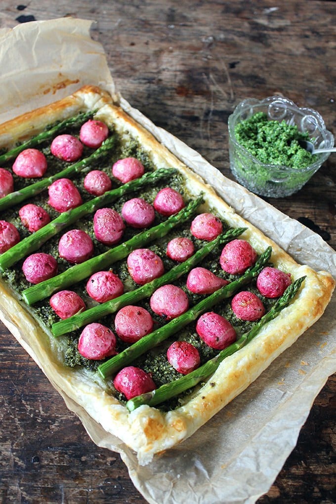 A tart with radishes and asparagus on a wooden table.