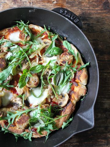 Close up of skillet pizza with toppings on wooden table