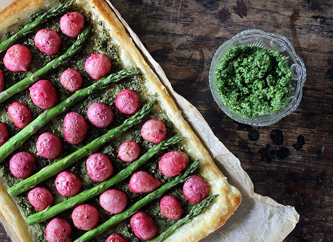 A tart with radishes and asparagus on a wooden table.