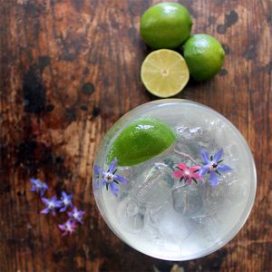 A glass of cocktail with edible flowers.