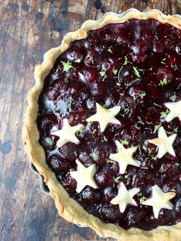 Close up of a cherry pie with pastry stars on half of it.