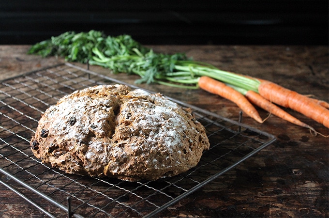 Cinnamon Carrot Soda Bread on a cooling rack in front of carrots