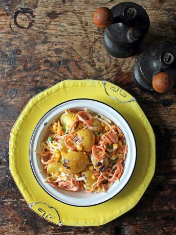 Salad on a plate, with potatoes, apple and carrots.