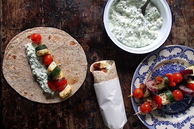 A table with souvlaki and wraps being made.