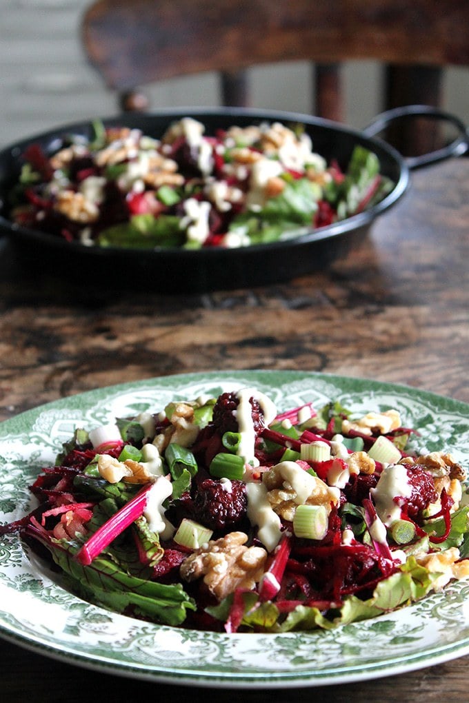 Beetroot salad shown on a table next to serving dish of the Beet, Blackberry and Apple Salad with Lemon Tahini Dressing. Get the vegan salad recipe. 