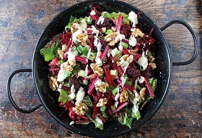 Blackberry Apple Beet Salad with Tahini Dressing in a black serving dish on wooden table.