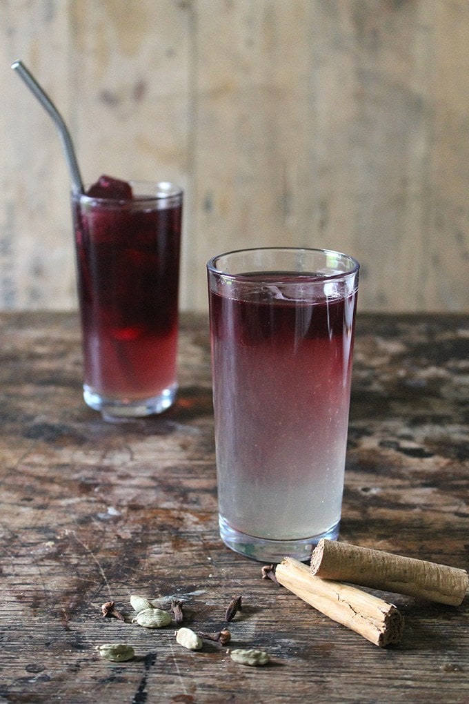 A tall glass with mulled wine ice cubes slowly melting into the mulled gin cocktail.